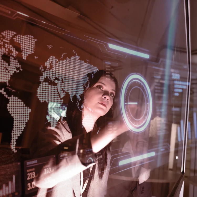 A business analyst manages global data flows and business metrics on a transparent, futuristic holographic display.