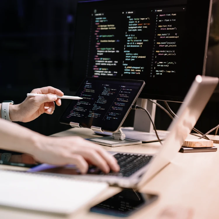 Developer reviewing source code on a monitor and tablet for data protection and compliance verification.