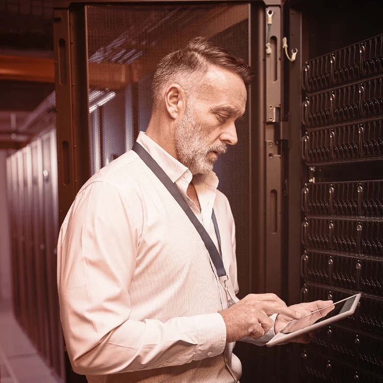 An IT expert checks server security in a data center using a tablet to ensure data protection and corporate digital resilience.