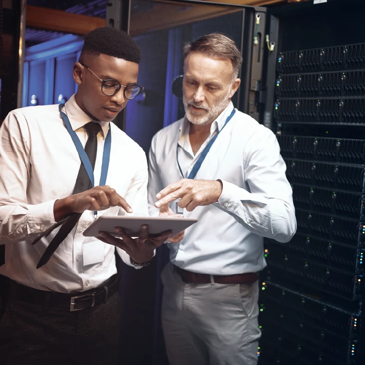 Two technicians conduct an On-site Inspection by monitoring data on a tablet in a server room.