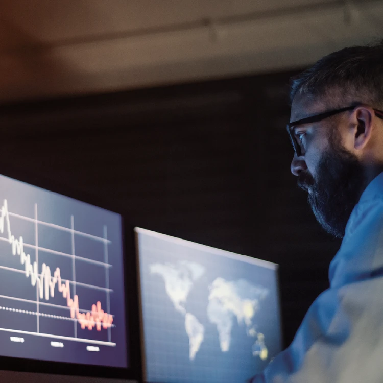 Analyst at computer monitoring data trends for process mapping and analysis.